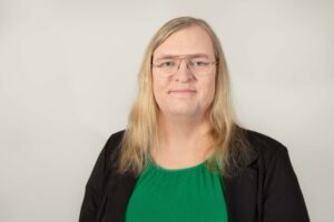 Eva is a white woman with glasses and long blonde hair.