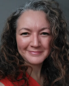 Karen is a white woman with fair wavy shoulder-length hair, smiling warmly at the camera.
