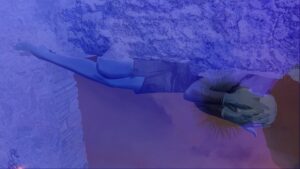 Blue abstract image with textured elements and superimposed on a figure who is lying down curled up.