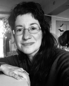 Gaelle is a white woman with glasses and dark wavy hair.